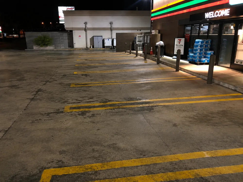 Stained convenience store parking lot before cleaning at night